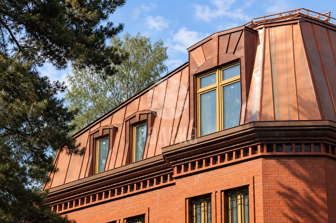 Copper mansard roof with dormer windows on a brick house in Elektrougli.