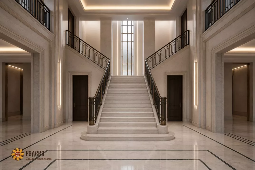 Symmetrical hall in Art Deco style with a light stone staircase, metal railings, and a high central window.